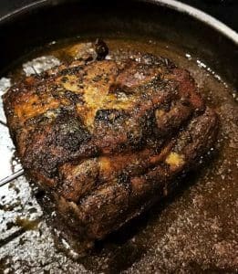 En välstekt köttbit som har lagats i ugn och ligger i en svart stekpanna.
