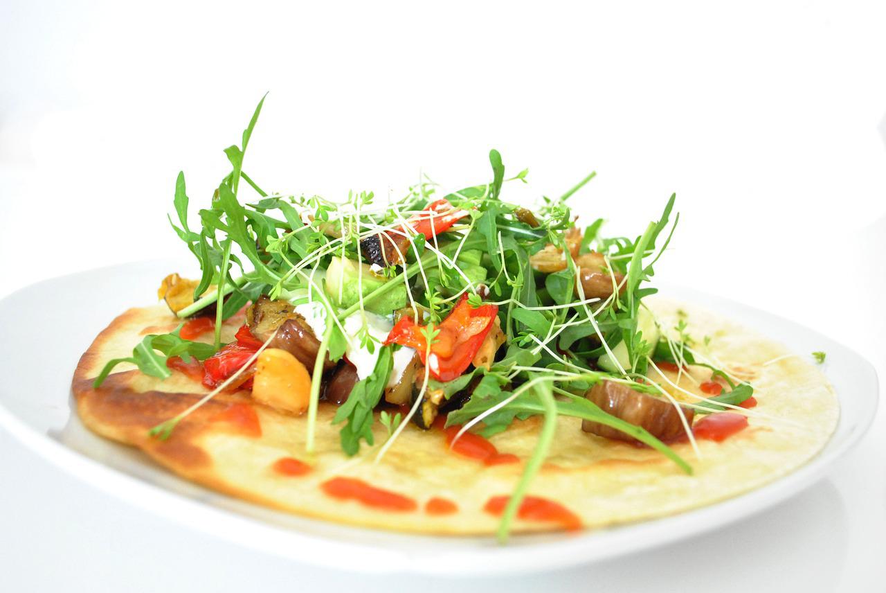 Tortilla med grönsaker, sallad och sås på en vit tallrik. Tortilla med grönsaker, sallad och sås på en vit tallrik.